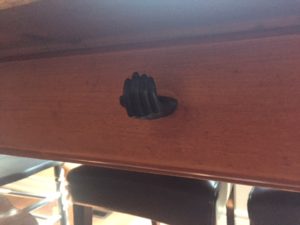 black hand knob is the pull for a pine drawer. The hand is cupped as if someone was about to put change in it.