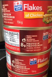 stacked cans of Maple Leaf brand chicken breast, labelled in red, "Flakes of Chicken"