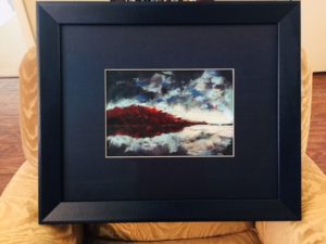 a red mountain reflected in ice-blue water with a dark blue sky and white clouds. Although it's pastel, it's very vivid