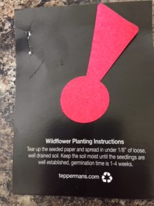 Black card with red exclamation point in felt, which is the company's logo, and an explanation underneath that the felt piece is a wildflower starter and contains seeds