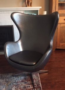 Silver vinyl chair on a metal base. Chair is one big molded piece with arms and a backrest that comes loosely around the side of the head. Its a big char!