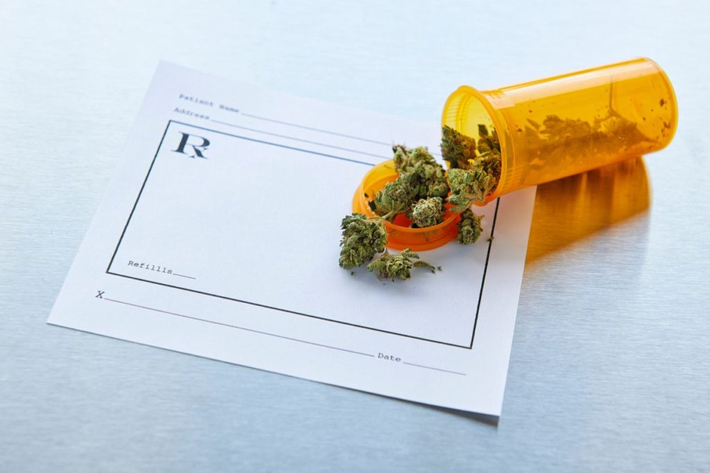 Prescription bottle of pot spilled out onto a prescription pad