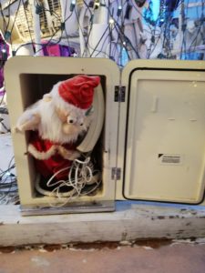 A small santa peeks out of an old telephone box