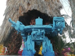 giant blue robot in front of a palm tree