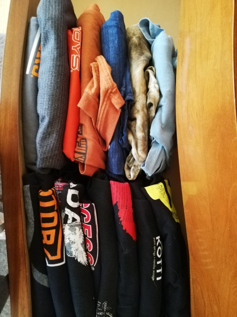 Dozens of Derek's T-shirts folded into rectangles and stood on end in his half-full dresser drawer