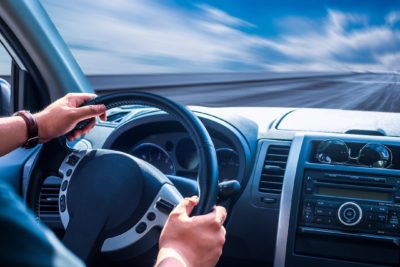 hands on the steering wheel of a car on a highway