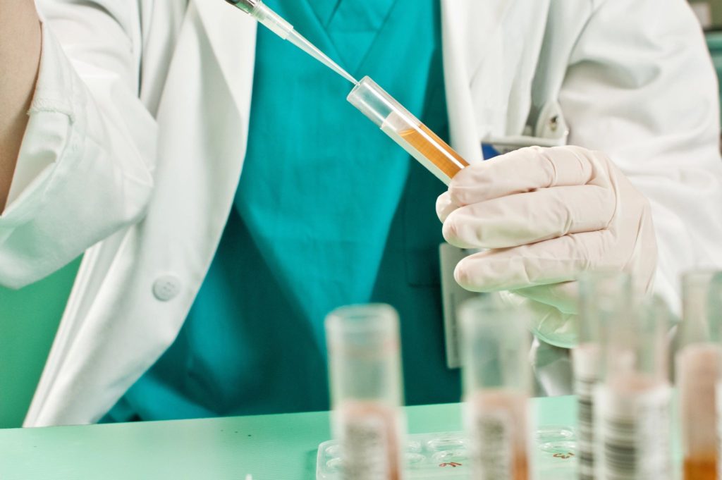 scientist filling beakers with gold coloured liquid