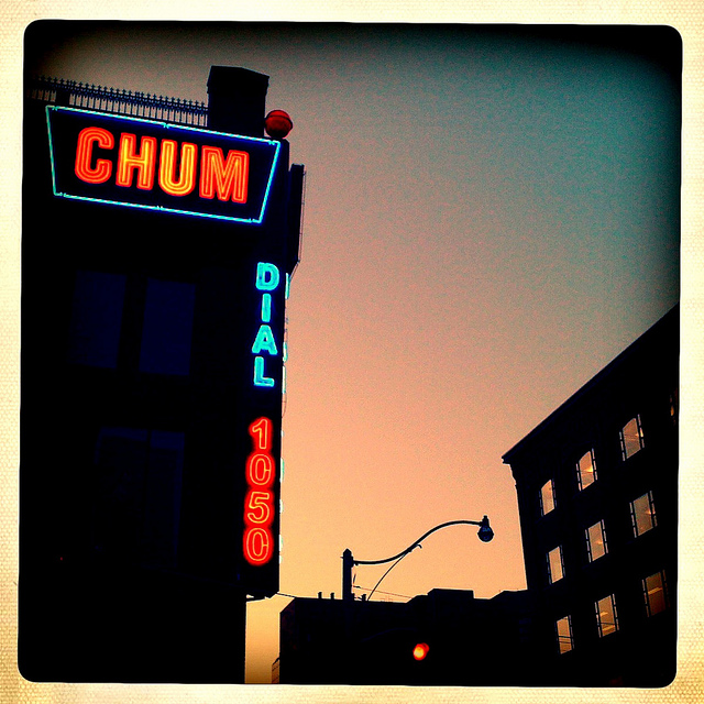 Dusk photo of the iconic CHUM sign with Dial 1050, all lit up in red and blue