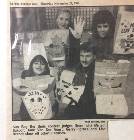 Black and white photo from the Toronto Sun, dated Thursday Nov. 22, 1990. A Sun staffer, our promo director, Gerry and me holding paper bags made into goalie helmets for a contest. 