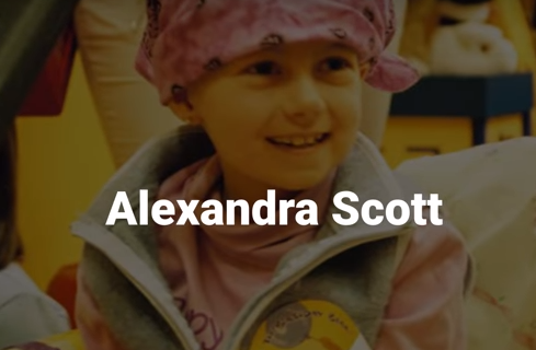 screen snip showing a young girl in a bathrobe and head covering, obviously in a hospital and suffering from cancer, with the name Alexandra Scott below her