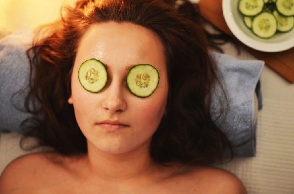 Woman lying on a towel in a spa with cucumber slices over her eyes