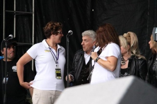 Dennis DeYoung, Leigh Robert and I in close proximity, looking like we are in a conversation. Microphones and other equipment is on the stage, ready for a performance. 