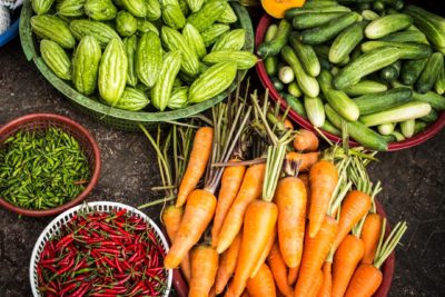 bowls of freshly picked vegetables including carrots, red peppers, cucumbers and zucchini
