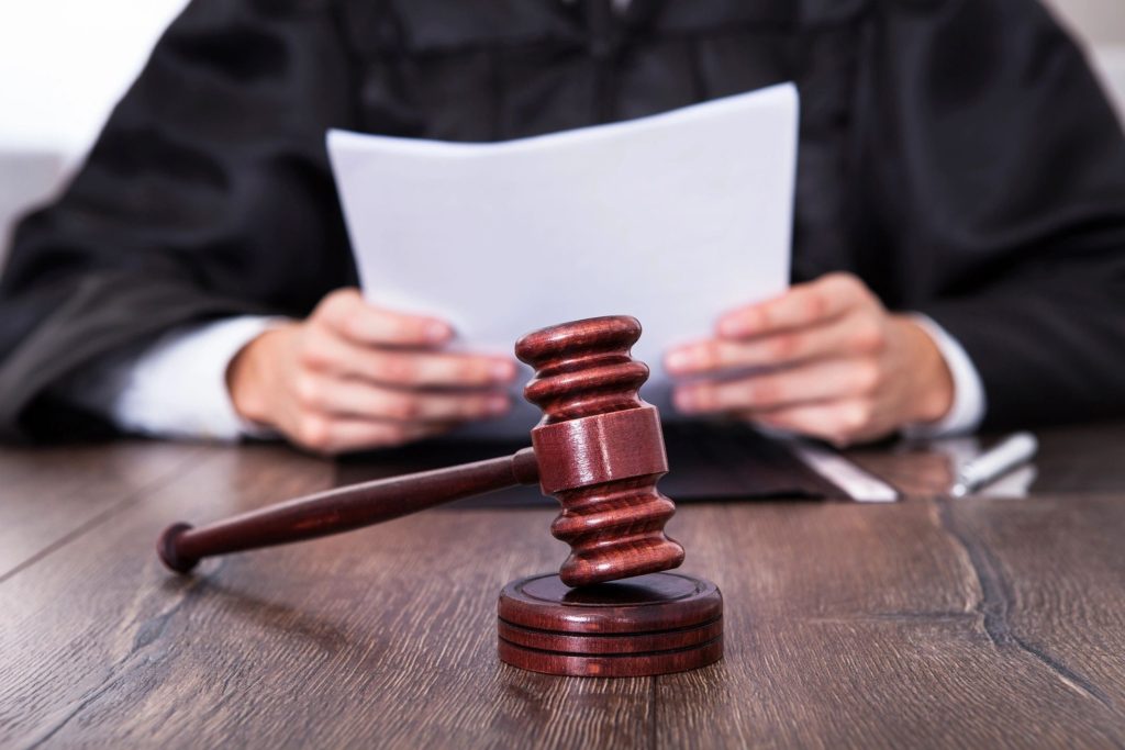 hands of a judge who is reading a paper with a gavel in front of them