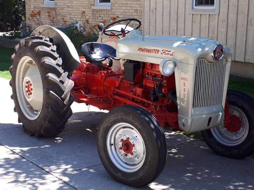 Old Powermaster Ford tractor from the 40s has new tires, has been completely redone and painted grey and white with a black seat. 