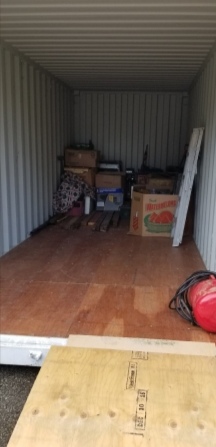 Inside the storage container. It's clean and white with a plywood floor and has about 85% capacity still to be filled. A few boxes are inside.