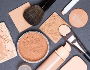 a selection of makeup in tubes, bottles and powder with brushes