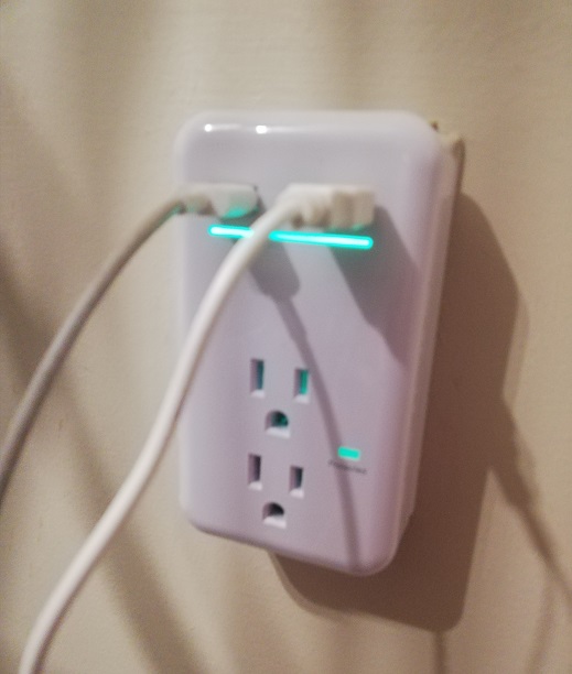 White plug looks like a regular outlet but it's plugged into the outlet. It has two plugs and two USB ports for cords. 