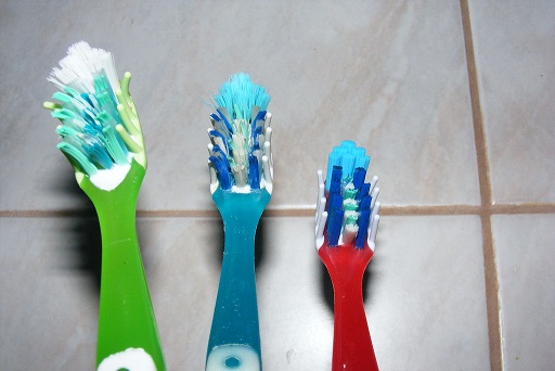 Three plastic toothbrush heads of varying sizes