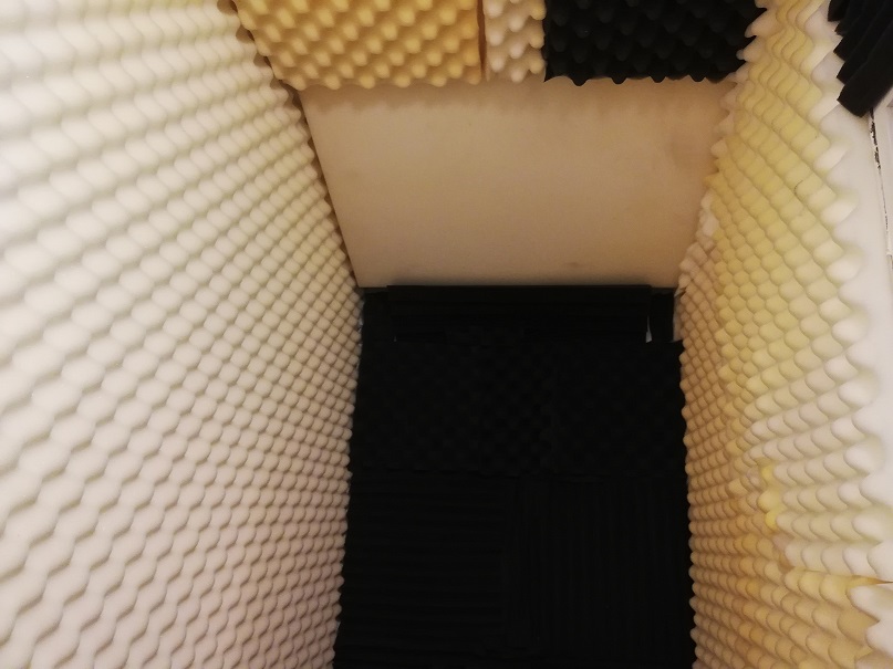 The view inside the deep closet with white acoustic foam on the walls and ceiling and brown foam straight ahead on the end wall. 