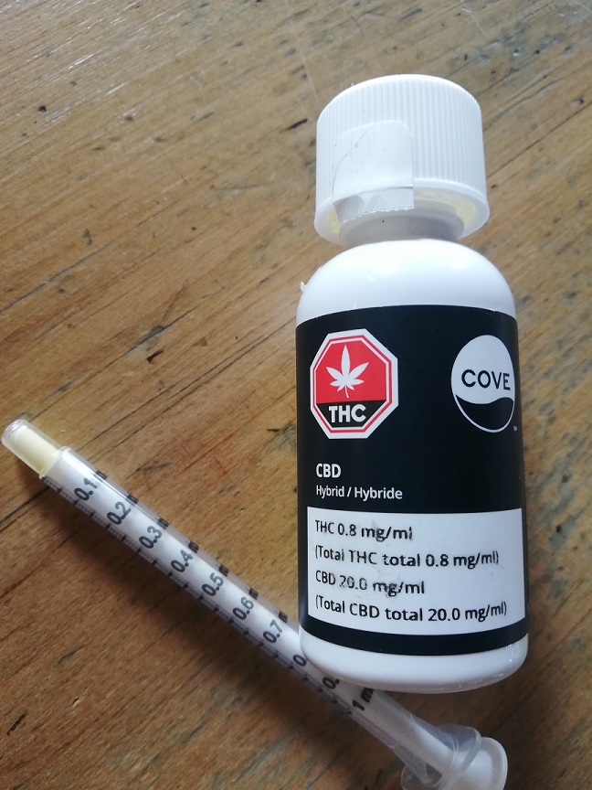 White vial with black label. Cover CBD Hybrid, 20 mg/ml. THC total is .8 mg/ml. 