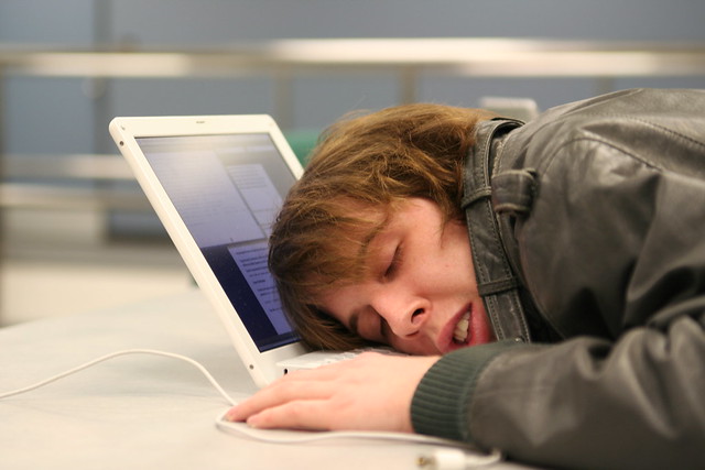 woman with her head on her open laptop, sleeping