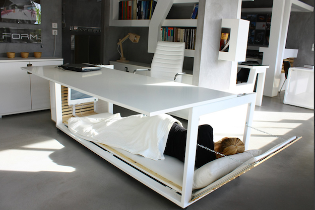 The sleep desk from Target is a large, white desk with a full-size bottom platform that has a bedroll and pillow. 