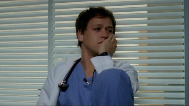 TR Knight as George O'Malley, looking sad with his hand on his face, in a scene from Grey's Anatomy