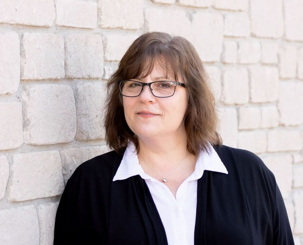 Me wearing a white shirt and black blazer against a brick wall - business portrait style