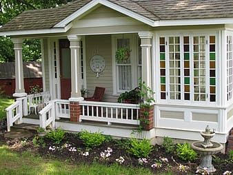 tiny home is beige siding with white accents and a flowerbed out front