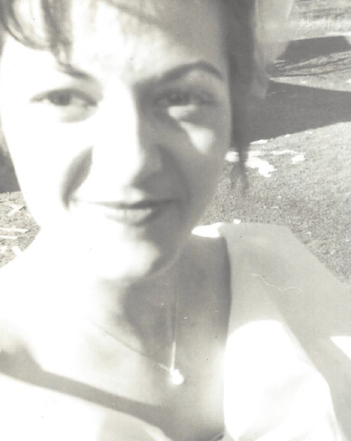 A black and white closeup of my Mom dressed up, with her hair up, smiling slightly and looking beautiful with dark hair and eyes. 