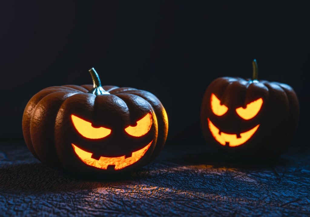 Two lit, carved pumpkins with slightly menacing faces