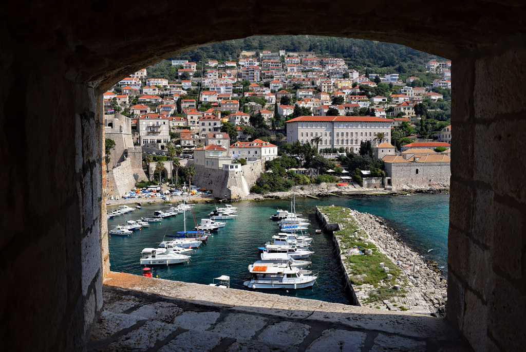 view through a stone window opening to a bay and a medieval-looking town on a hill
