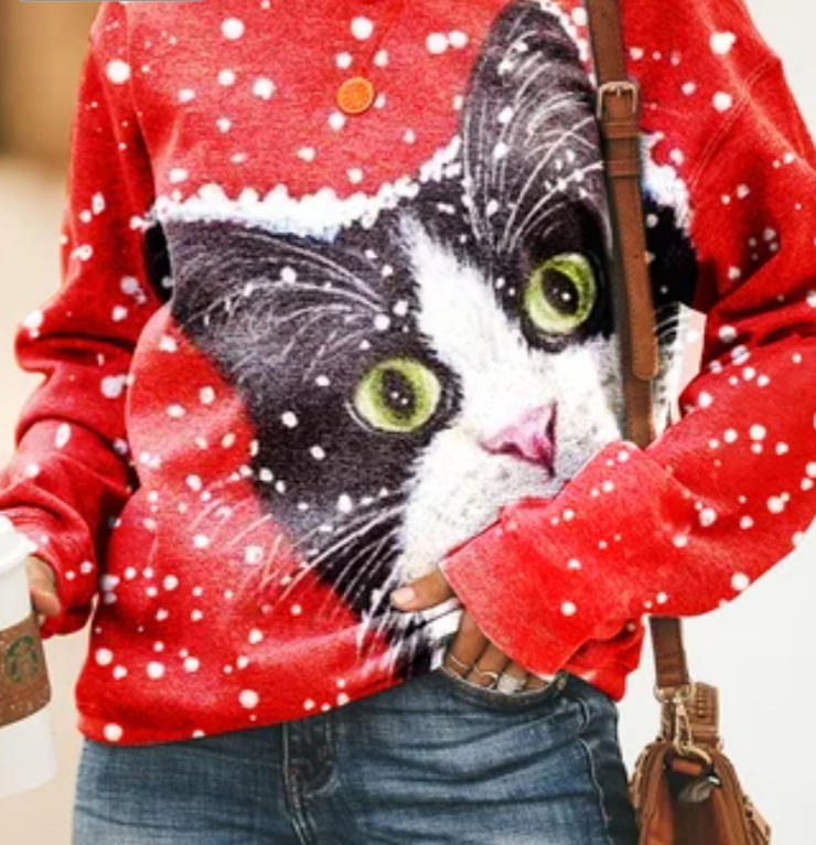 The torso of a woman wearing a bright red sweater with a huge cat face covering almost the entire front of it.