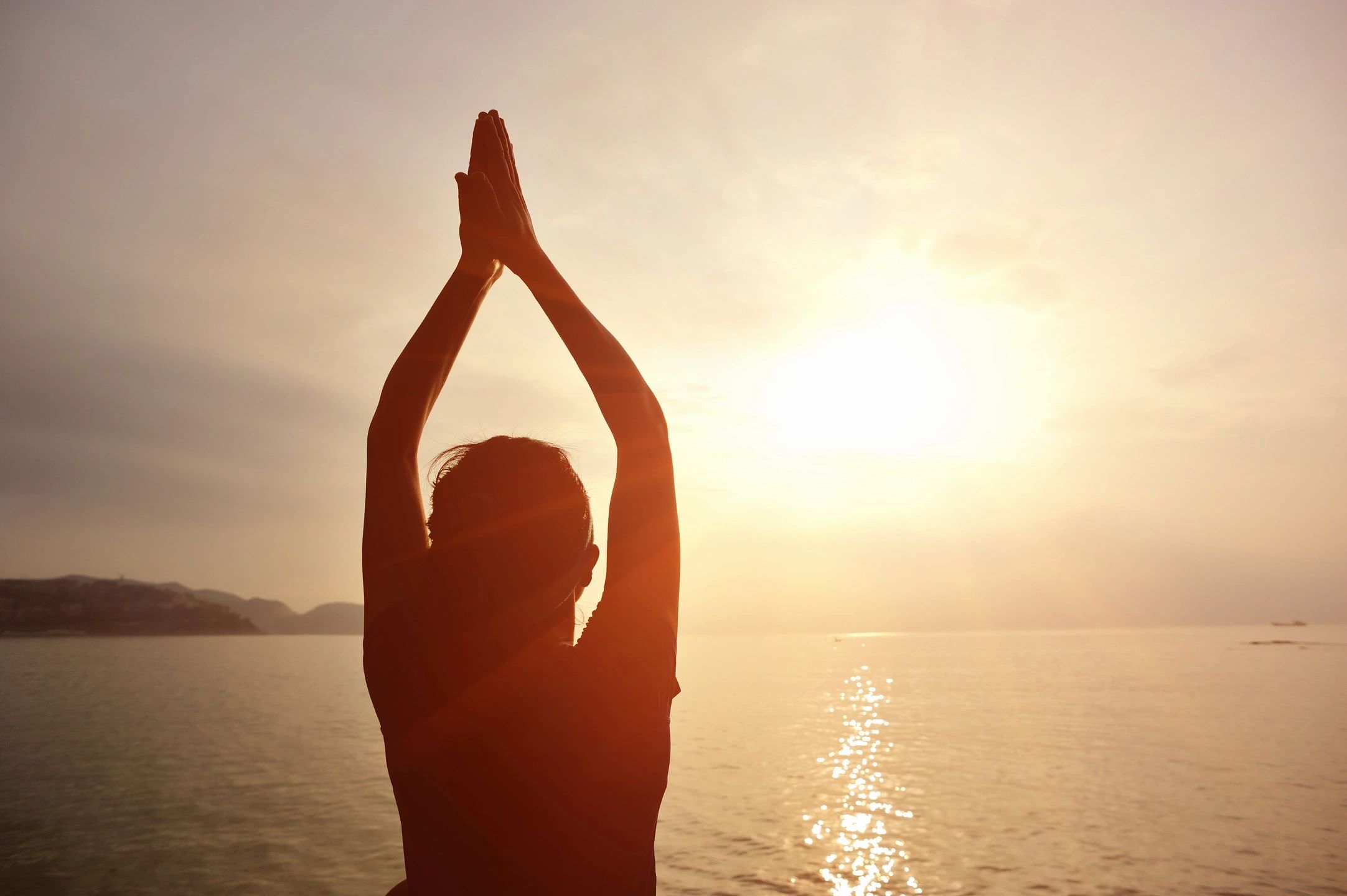 woman meditating as the sun rises
