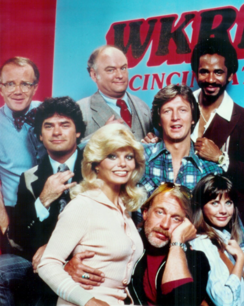 The cast of WKRP poses in front of the call letters on a wall
