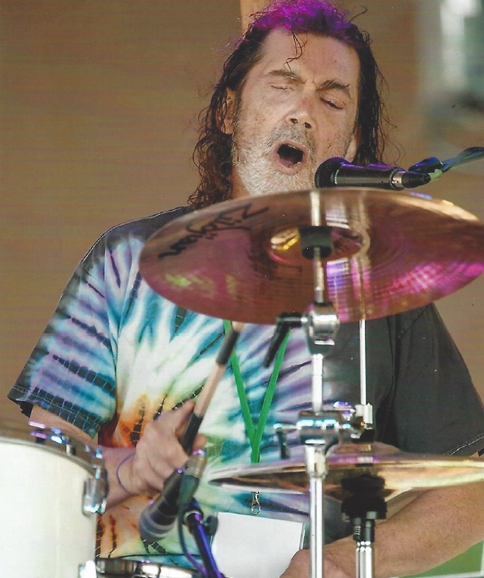 Brother Dave, eyes closed, drumming, with purple lights around him.