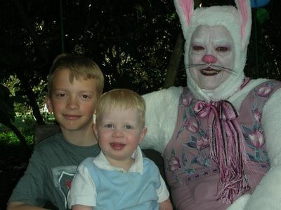 Middle-aged man made up as a bunny, including white makeup on his face and eyebrows. Two young boys sit beside him, smiling.