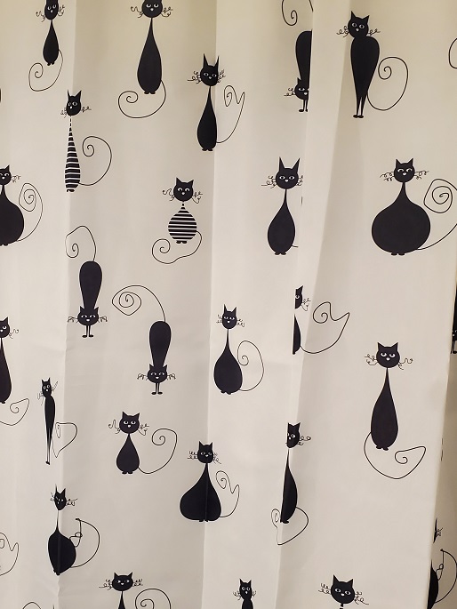 White shower curtain with random black cats in cartoon form.