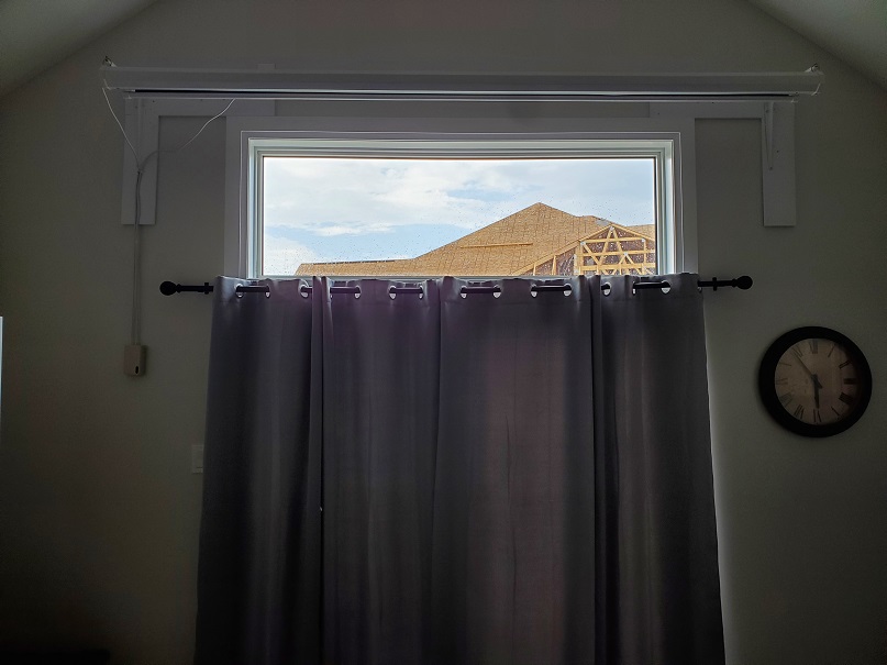 Blackout curtains close the patio door to incoming light. The open transom above shows the roof line of the condos being built. 