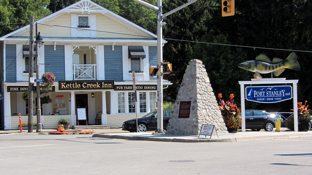 The Kettle Creek Inn, a large blue and white building, and the Port Stanley welcome sign that says shop, dine, stay. It has a big fish on top of it. 