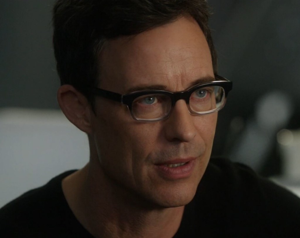 Close up of Tom Cavanagh, 50-something, dark haired man with blue eyes, wearing glasses.