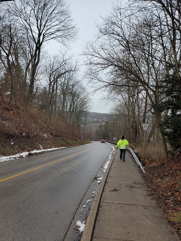 A photo of Derek walking down Schoolhouse Hill. Further ahead is a car, which is obviously a great deal lower than Derek. 