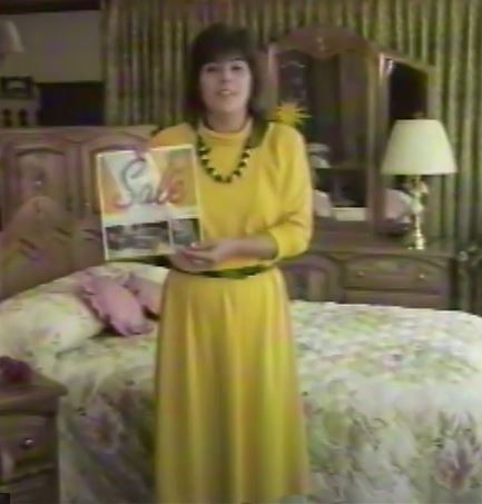 Me at 25 wearing a tight-fitting gold dress and black belt. Slim. Holding up a sale flyer for the client, Tanner and Pearson furniture. 