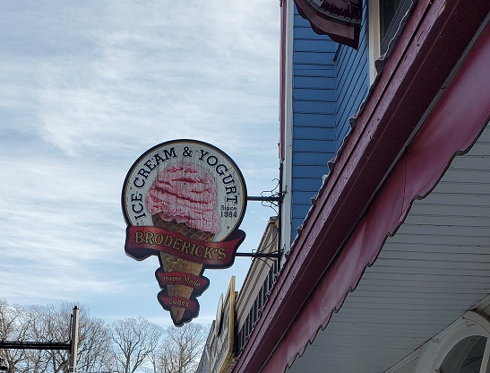 Broderick's Ice Cream and Yogurt sign is in the shape of a large cone of ice cream. 