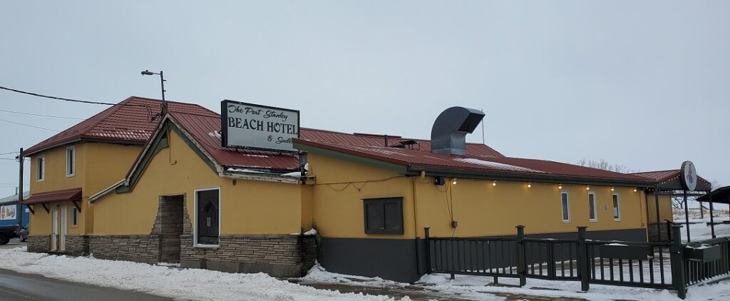 Long mustard yellow building with a red roof at the beach houses the hotel and restaurant, virtually at the water. 