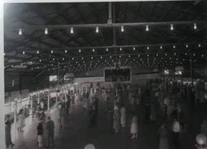 Photo of the dance floor with hundreds of bulbs on tracks overhead and hundreds of people on the massive wooden dance floor. 