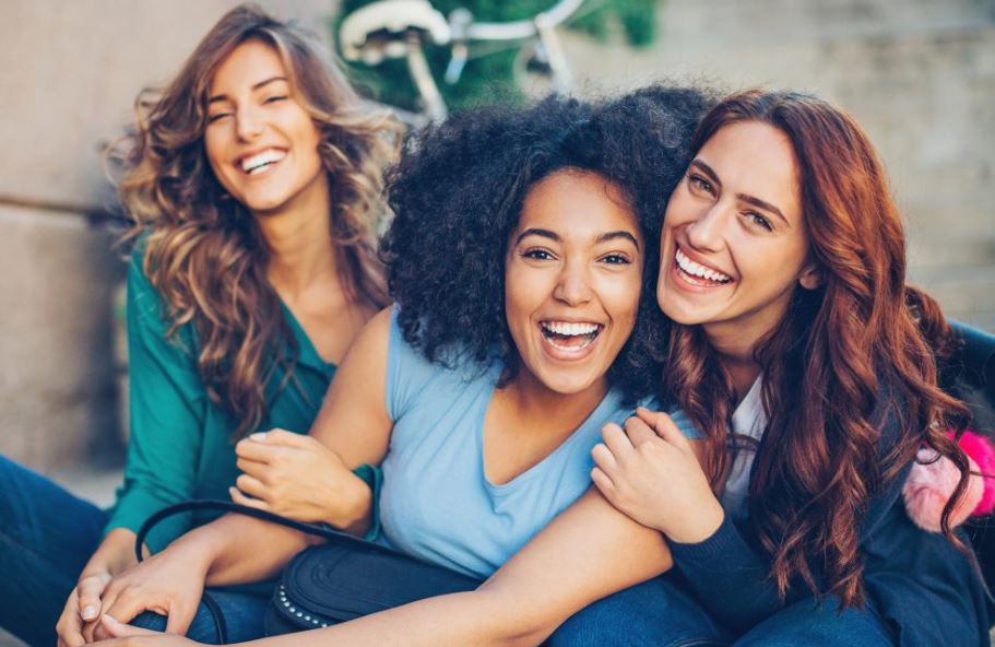 Three pretty young women of different ethnicities smiling for the camera