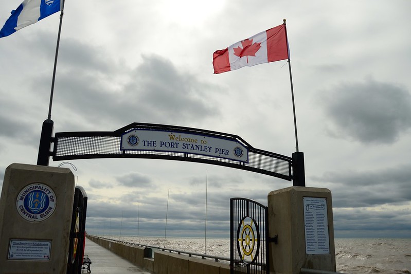 welcome signs at the gate on Port Stanley's pier with a large Canadian flag overhead