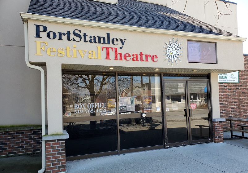 The front of Port Stanley Festival Theatre with black, yellow and red lettering and glass doors.